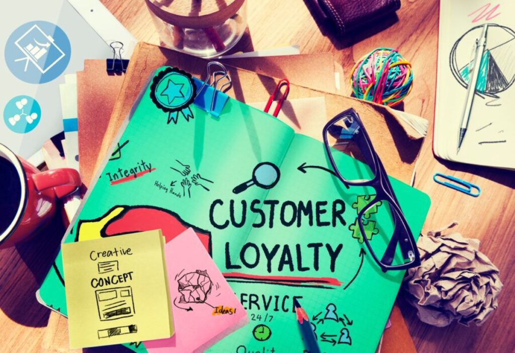 A desk scene featuring a notebook labeled "Customer Loyalty," sticky notes, glasses, and creative supplies, emphasizing service concepts.