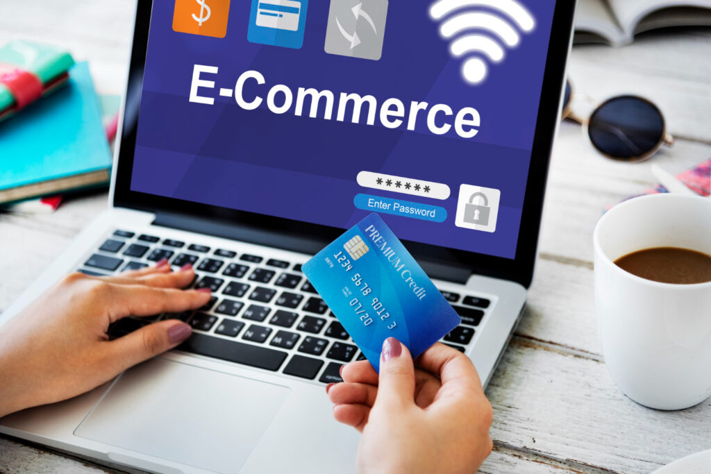 A person holds a credit card while logging into an e-commerce site on a laptop, with a coffee cup nearby.