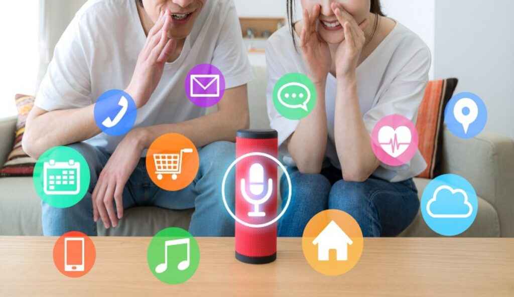 A man and a woman are sitting on a sofa, engaging with a red smart speaker surrounded by various app icons like shopping, music, and calendar.