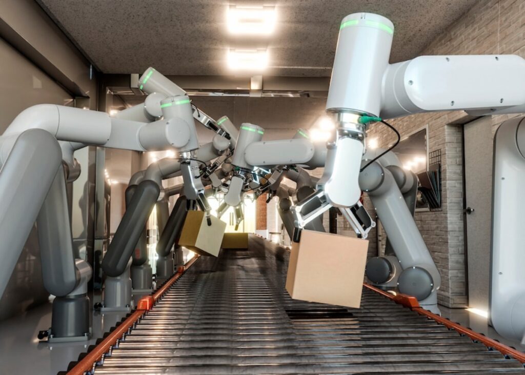 Robotic arms sorting packages on a conveyor belt in an industrial setting.