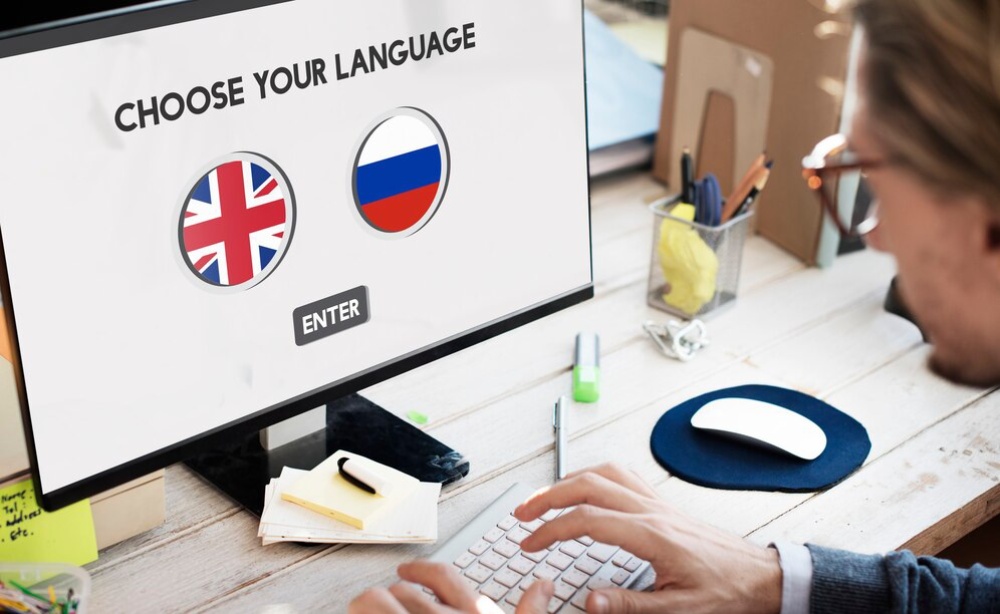  Man choosing between British and Russian flags on a language selection screen on his computer. 